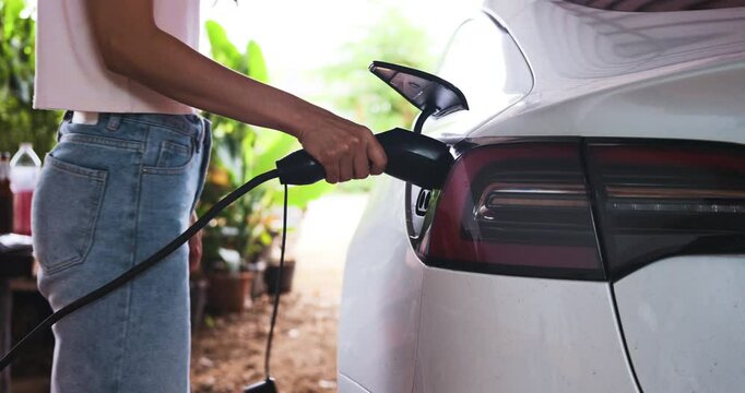 Business woman hand use ev car charge at home zero emission transport