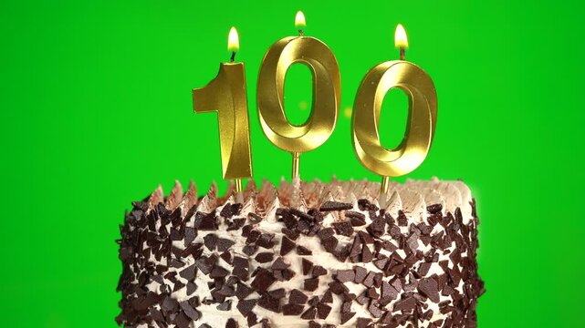 Burning candles number 100 on birthday cake against chroma key background. One hundredth birthday. Birthday and anniversary celebration