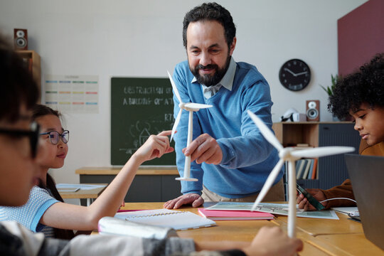 Educator engaging with students while explaining a wind turbine model during a classroom activity. Diverse group of students participating actively in the learning process - Powered by Adobe