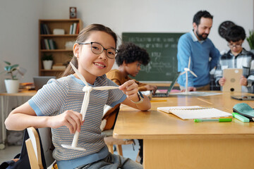 A group of students and a teacher engaging in a renewable energy lesson using wind turbine models in modern classroom