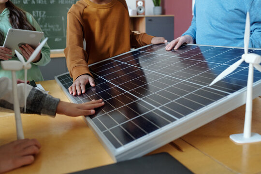 Students examining solar panels and wind turbines in classroom learning about renewable energy sources. Educational tools and technology enhancing understanding of sustainability