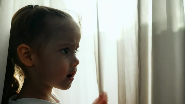 a child hides behind a curtain, overwhelmed with anxiety in natural window light