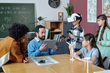 Teacher engaging students with virtual reality in classroom to explore concepts. Diverse group of middle school students participating in interactive learning experience