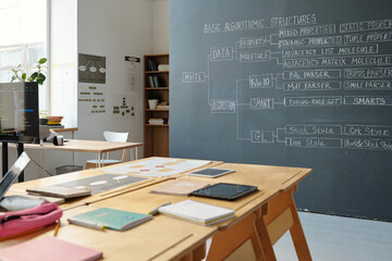 Organized modern office setup with digital devices on wooden desks and whiteboards displaying...