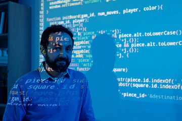 Portrait of man standing with face covered by projected programming code creating a tech ambiance....