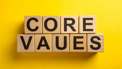 Defining Core Values Wooden blocks spelling out Core Values against a vibrant yellow background Simple bold typography emphasizes the importance of identifying and upholding core values in business