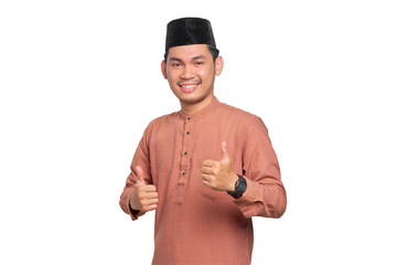 Smiling young Asian Muslim man showing thumbs up gesture isolated on transparent background