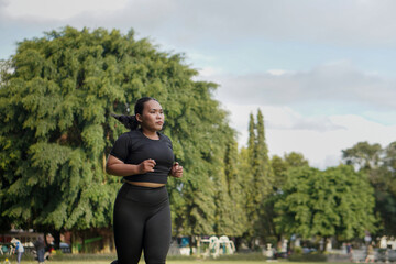 Confident Asian woman wearing sportswear jogging and running at outdoor public park
