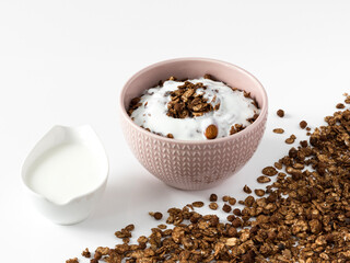 Chocolate granola with yogurt . Top view of a ceramic bowl with chocolate granola  and yoghurt on the white background . Muesli isolated , close-up . 