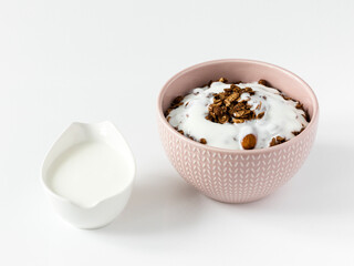 Chocolate granola with yogurt . Top view of a ceramic bowl with chocolate granola  and yoghurt on the white background . Muesli isolated , close-up . 