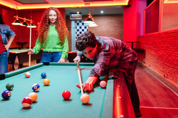 Friends enjoying a game of billiards in a vibrant bowling alley and arcade video game room, creating lasting memories
