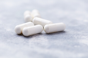 Creatine capsules on bright wooden background. Soft focus. Close up. Copy space	