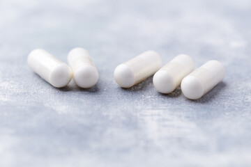 Creatine capsules on bright wooden background. Soft focus. Close up. Copy space.	
