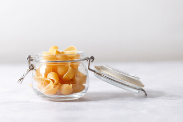 Raw uncooked dried Conchiglie shell pasta. Italian seashells pasta in lock lid jar on white background.