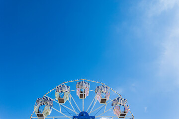 Colorful ferris wheel at a fairground under a clear blue sky showcases festive atmosphere and...