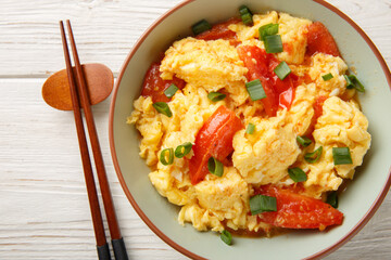 Stir-fried tomato and scrambled eggs is a common dish in China closeup on the plate on the wooden table. Horizontal top view from above