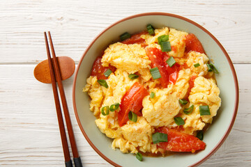scrambled eggs with tomatoes, chinese food closeup on the plate on the wooden table. Horizontal top view from above