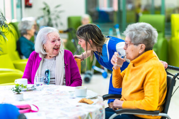 Nurse assisting elderly woman drinking water in nursing home