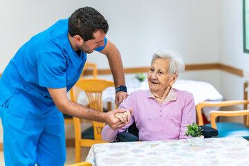 Male nurse assisting elderly woman in nursing home