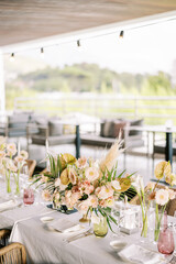 Bouquets of flowers stand on a served table in a restaurant with a panoramic view