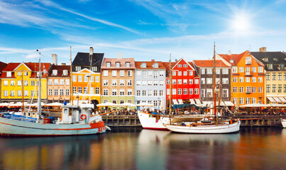 Naklejka premium Copenhagen colored building in Nyhavn with blue sky and sun, Denmark