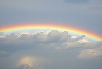 Elegant A rainbow arches over the clouds after a refreshing rain.