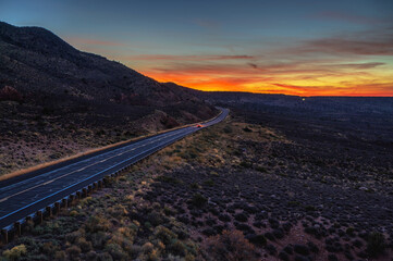 Remote road passes Dead Indian Canyon toward the Grand Canyon National Park, illuminated by a vivid Arizona sunset.