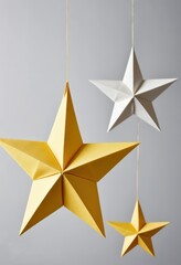 Obraz premium Three charming stars, two in bright white and one in sunny yellow, dangle gracefully from a delicate string, creating a whimsical, festive atmosphere.