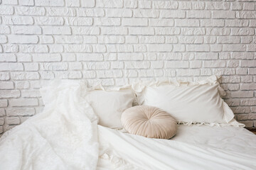 Comfortable bedroom setup with white brick wall and soft bedding during daytime