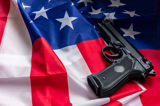 Black handgun lying on United States flag raising concerns about gun control