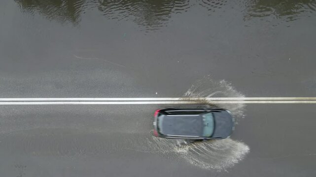 Aerial view of city traffic with cars driving on flooded street after heavy rain. Problems with road drainage system.