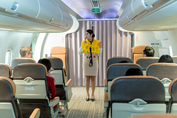 Flight attendant demonstrating life vest inflation to passengers during in-flight safety briefing on a commercial airplane for emergency preparedness awareness