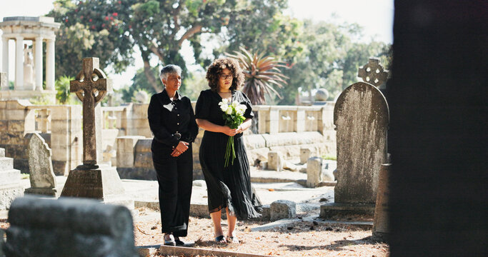 Sad, people and mourning with flowers at cemetery for death ceremony, memorial service or respect. Funeral, women or floral bouquet by tombstone for burial support, loss and grieving with remembrance