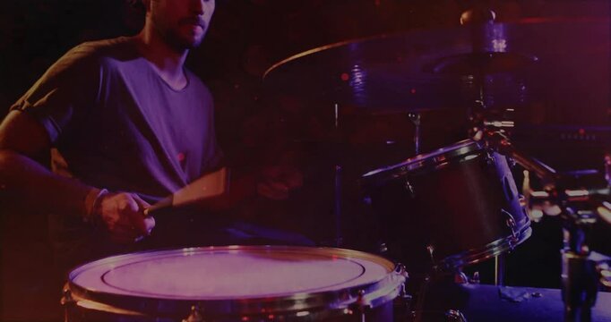 male drummer playing drum kit on dimly lit stage, showing animated sound waves for music production