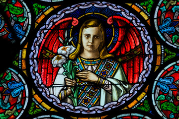 Stained glass (19th century) of an nice angel in heaven with flowers.