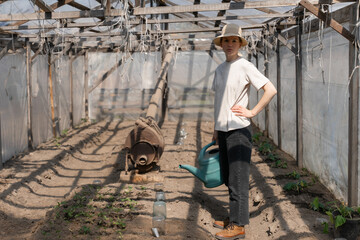 Young Woman Gardener Holding Watering Can in a green house