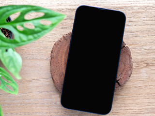 A minimalist flat-lay composition featuring a modern smartphone with a blank black screen over a...