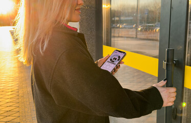 Woman locking smartlock on the entrance door using a smart phone. Concept of using smart electronic locks with keyless access.
