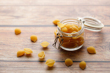 Raw uncooked dried Conchiglie shell pasta. Italian seashells pasta in lock lid jar on wooden...