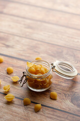 Raw uncooked dried Conchiglie shell pasta. Italian seashells pasta in lock lid jar on wooden background.