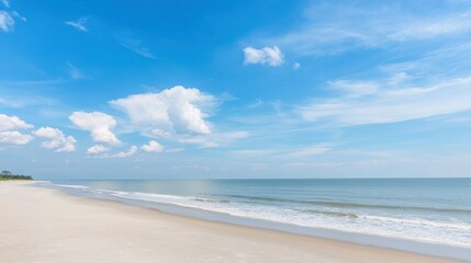 Obraz premium A beach scene with a clear blue sky and white clouds.