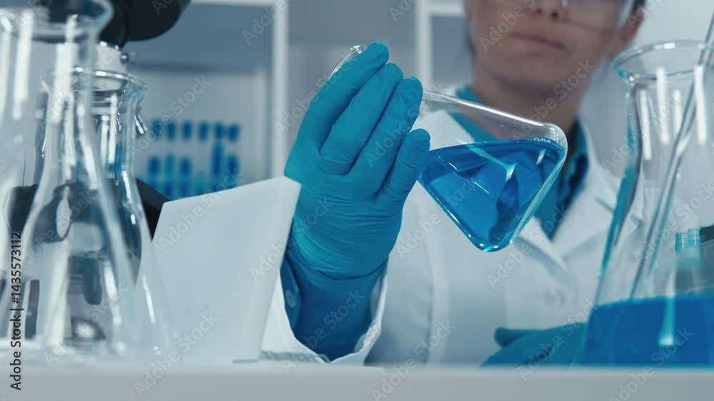 Poster a dedicated scientist in a white lab coat carefully examines blue solutions using laboratory glasswa