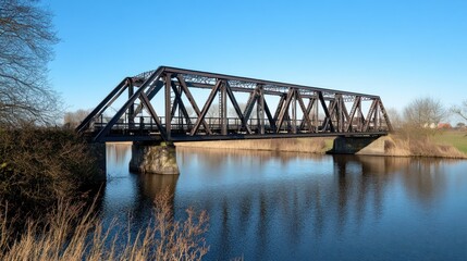 Obraz premium A steel truss bridge spans a wide river under a blue sky