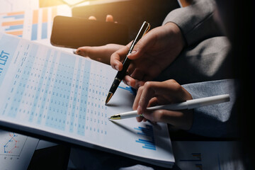 Group of confident business people point to graphs and charts to analyze market data, balance sheet, account, net profit to plan new sales strategies to increase production capacity.