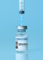 Rotavirus vaccine bottle and syringe placed on a clean blue background, representing healthcare, medical science, immunization awareness, and disease prevention. Banner with copy space