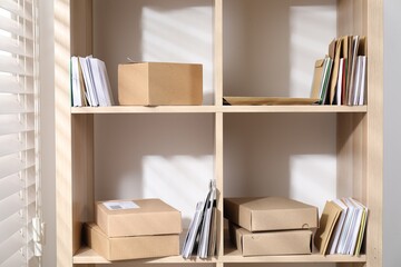 Different paper envelopes and parcels on wooden shelves in post office
