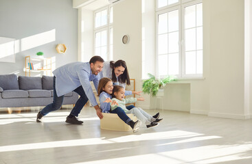 Cheerful and active family with kids enjoying leisure time and playing together at home. Parents giving kids a ride in a box, creating a joyful bonding moment filled with fun and laughter.