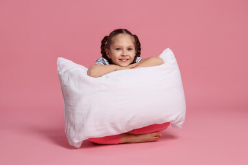 Cute girl with pillow on pink background