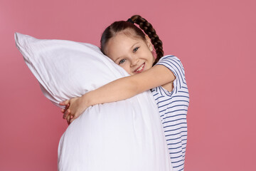 Cute girl with pillow on pink background