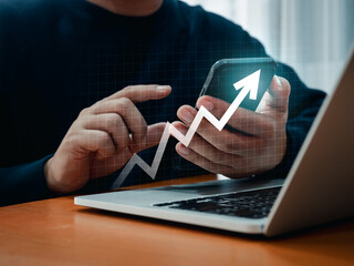 Investment technology, financial, return on investment - ROI concepts. Rising digital arrow appears while businessman using smart mobile phone for analyzing financial data stock market at workplace.